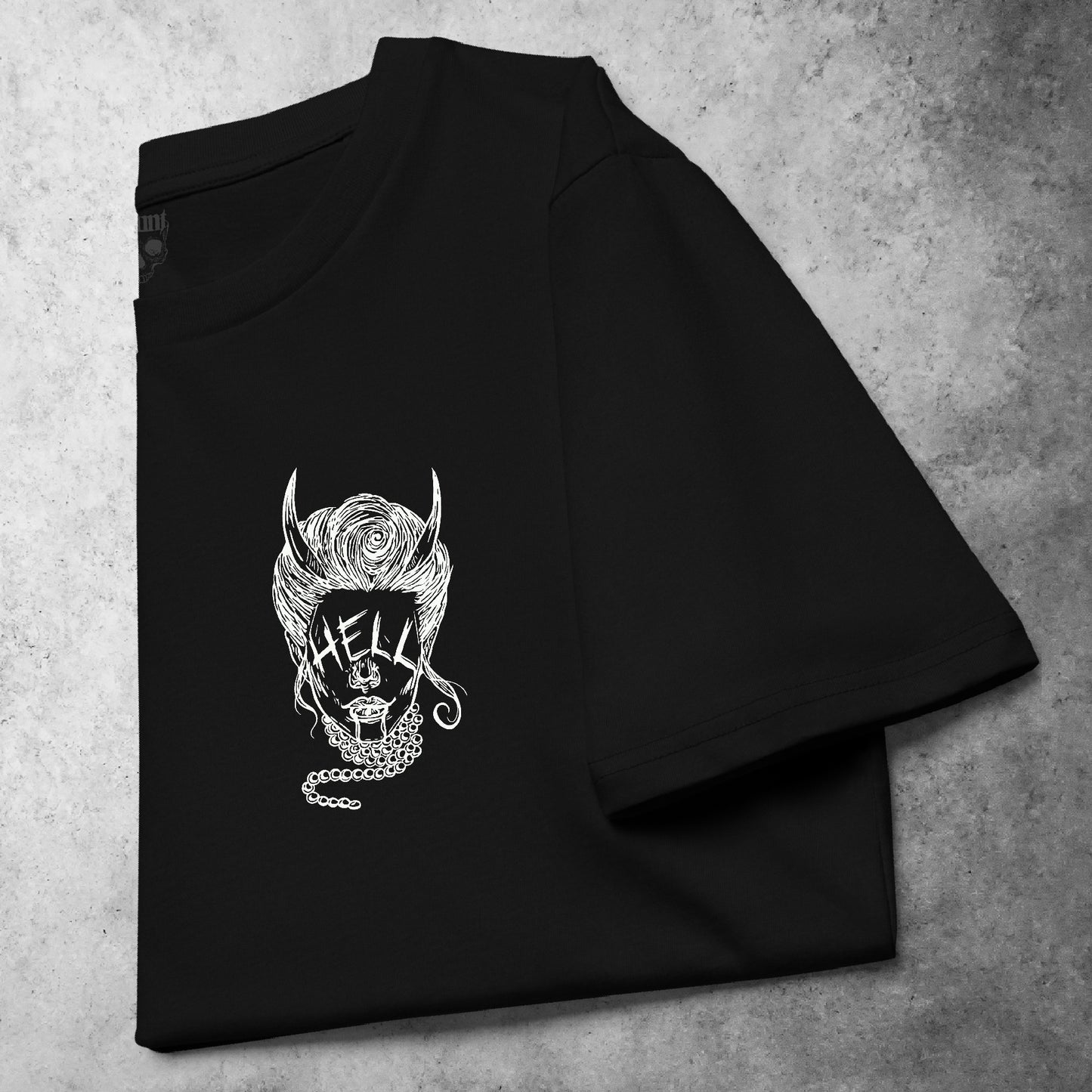 Folded front view of the Devil Eyes t-shirt from the Haunt Pocket Collection, featuring a white design of a horned woman wearing pearls with the word 'HELL' in place of her eyes.