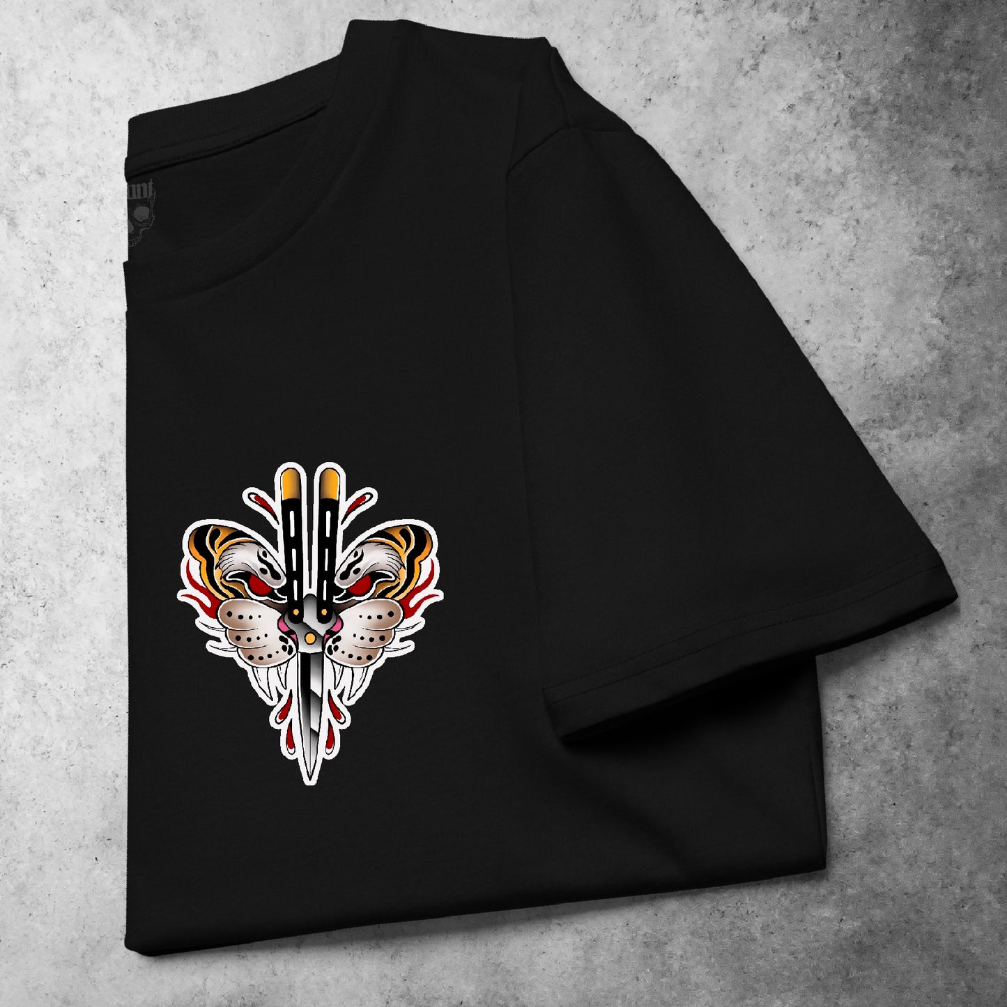 Folded black heavyweight t-shirt on concrete background, featuring Haunt’s Flutter Blade design — a bold tattoo-style butterfly with dual blades and fiery red-yellow detailing.