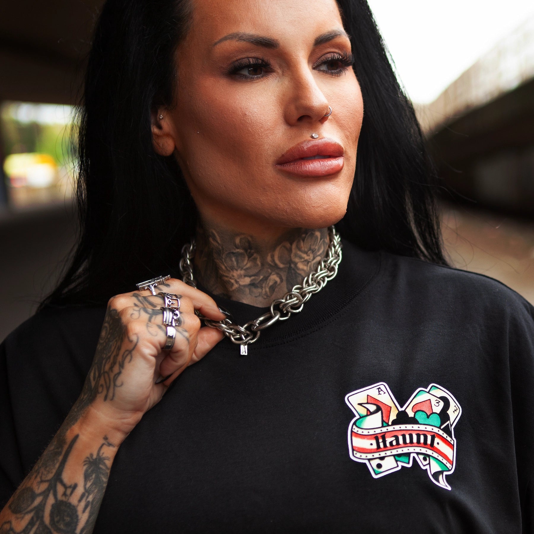 Close-up of tattooed model wearing Haunt’s Man’s Ruin t-shirt with playing card-inspired pocket design, photographed under an overpass in Bristol.