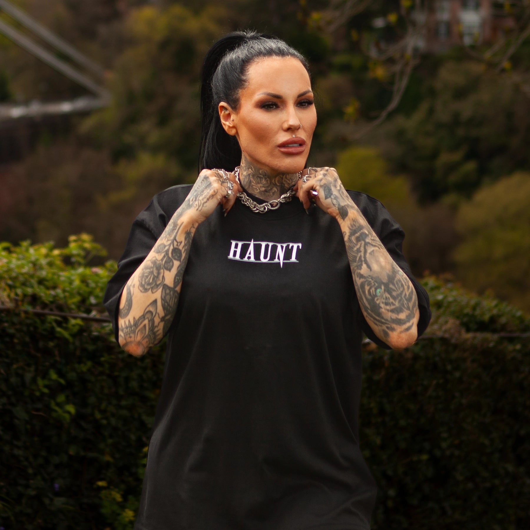 Front view of the Softcore Bloom premium t-shirt with HAUNT logo, worn by tattooed model standing in front of Bristol’s Clifton Suspension Bridge.
