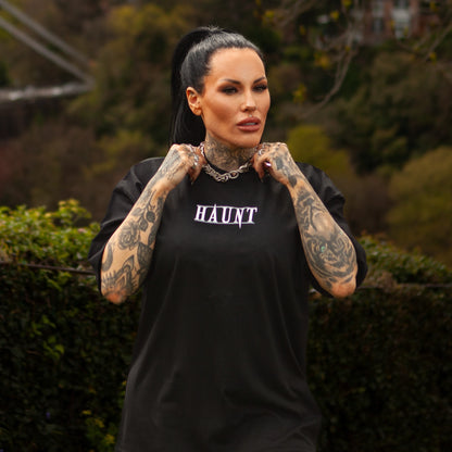 Front view of the Softcore Bloom premium t-shirt with HAUNT logo, worn by tattooed model standing in front of Bristol’s Clifton Suspension Bridge.